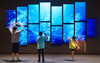 A group of people looking at a large screen.